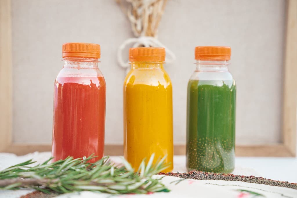Trois bouteilles de jus maison, rouge, jaune et vert